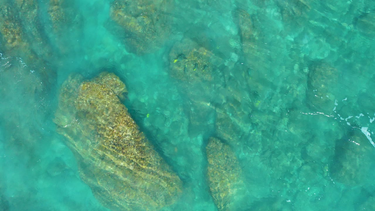 Overhead turquoise water above submerged rocks.