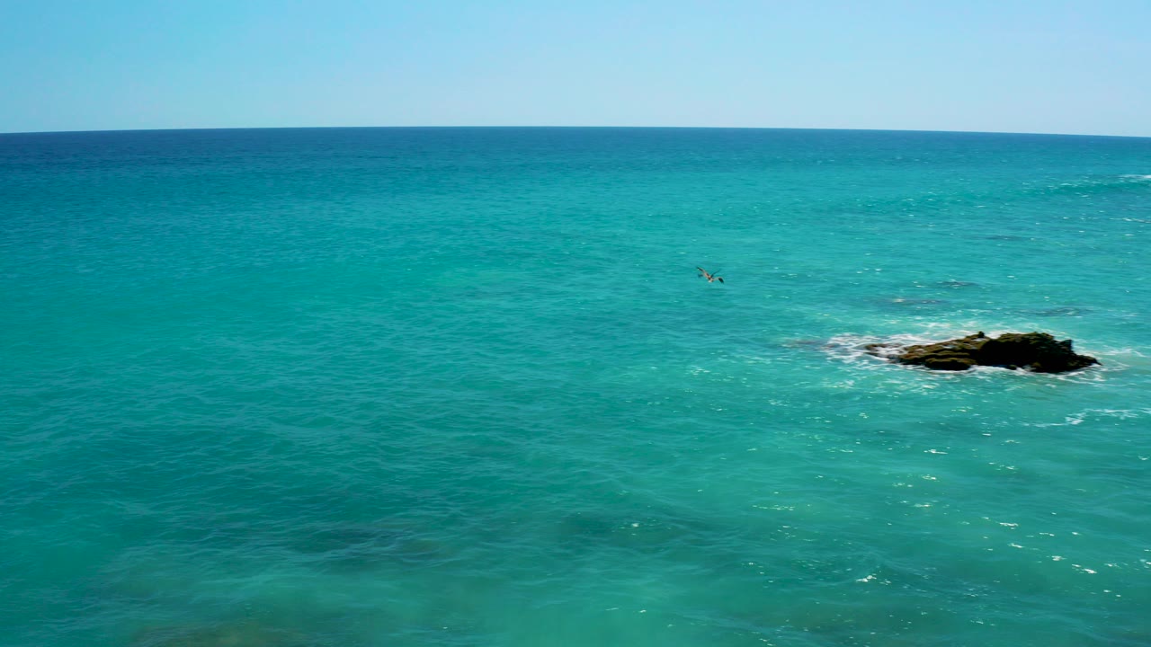 Turquoise ocean water with a dark rock outcrop and horizon