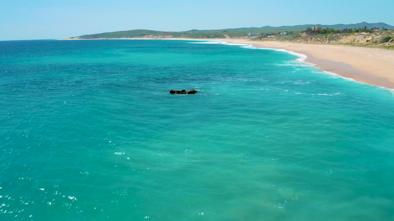 Turquoise sea beside a sandy beach with rocks offshore