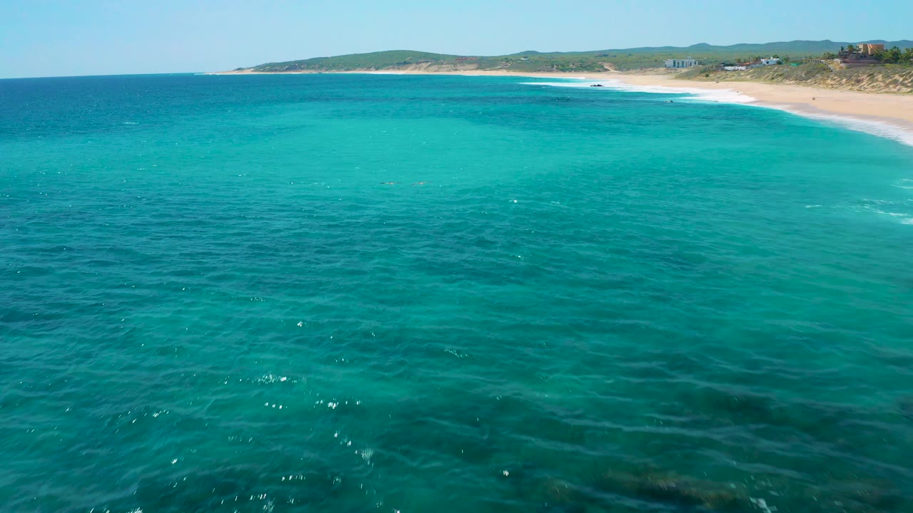 Bright blue ocean with shoreline and hills along the top of frame.