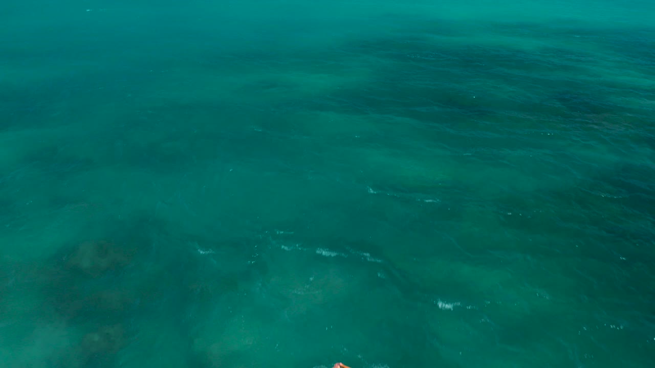 Aerial view of turquoise ocean with darker underwater patches.