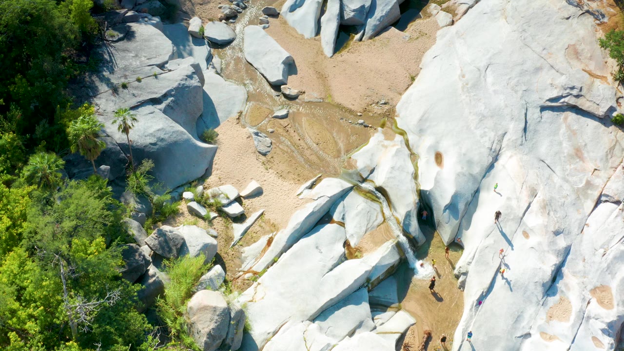 Aerial view of white rock slabs beside sandy channels and greenery.