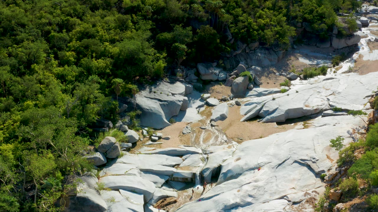 Wide aerial view of green trees around pale exposed rock.