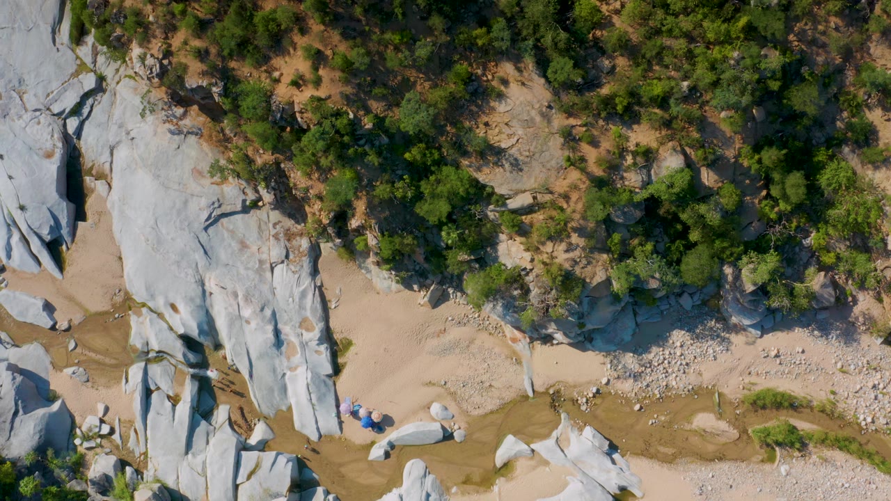 Top-down rocky wash with white stone slabs and green brush.