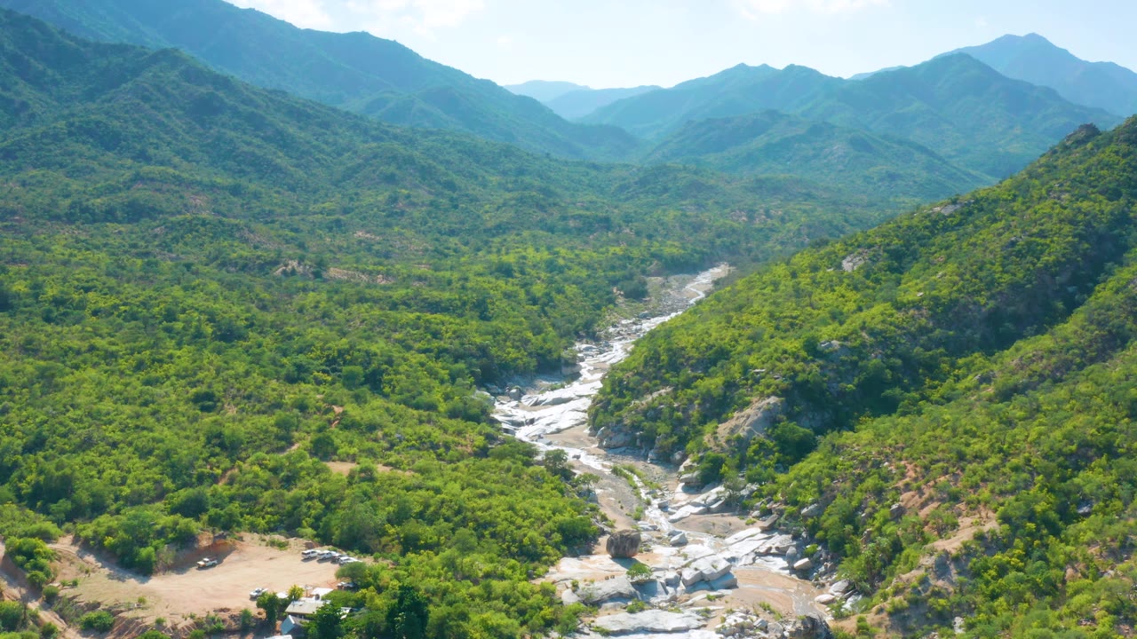 High view across a green mountain valley with white rock channel