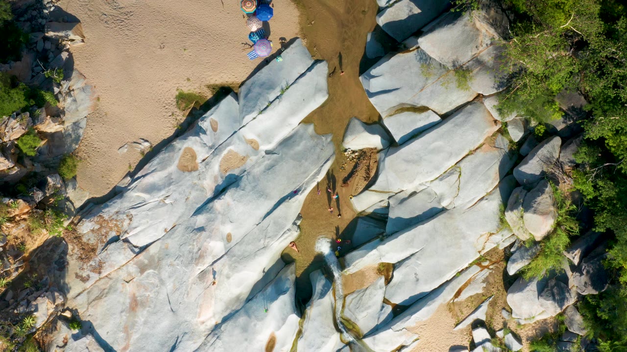 White rock slabs and sand seen from directly above with vegetation at the edges.