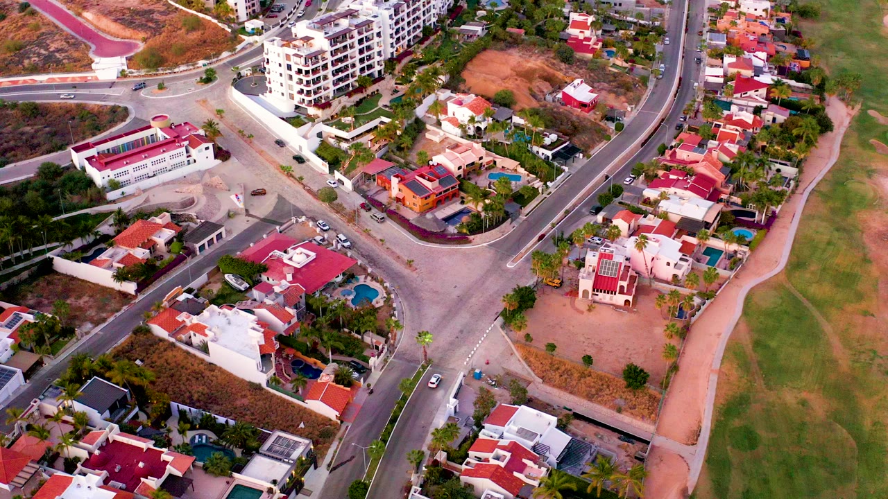 Aerial view of curved residential roads, houses, cars, and dry lots.
