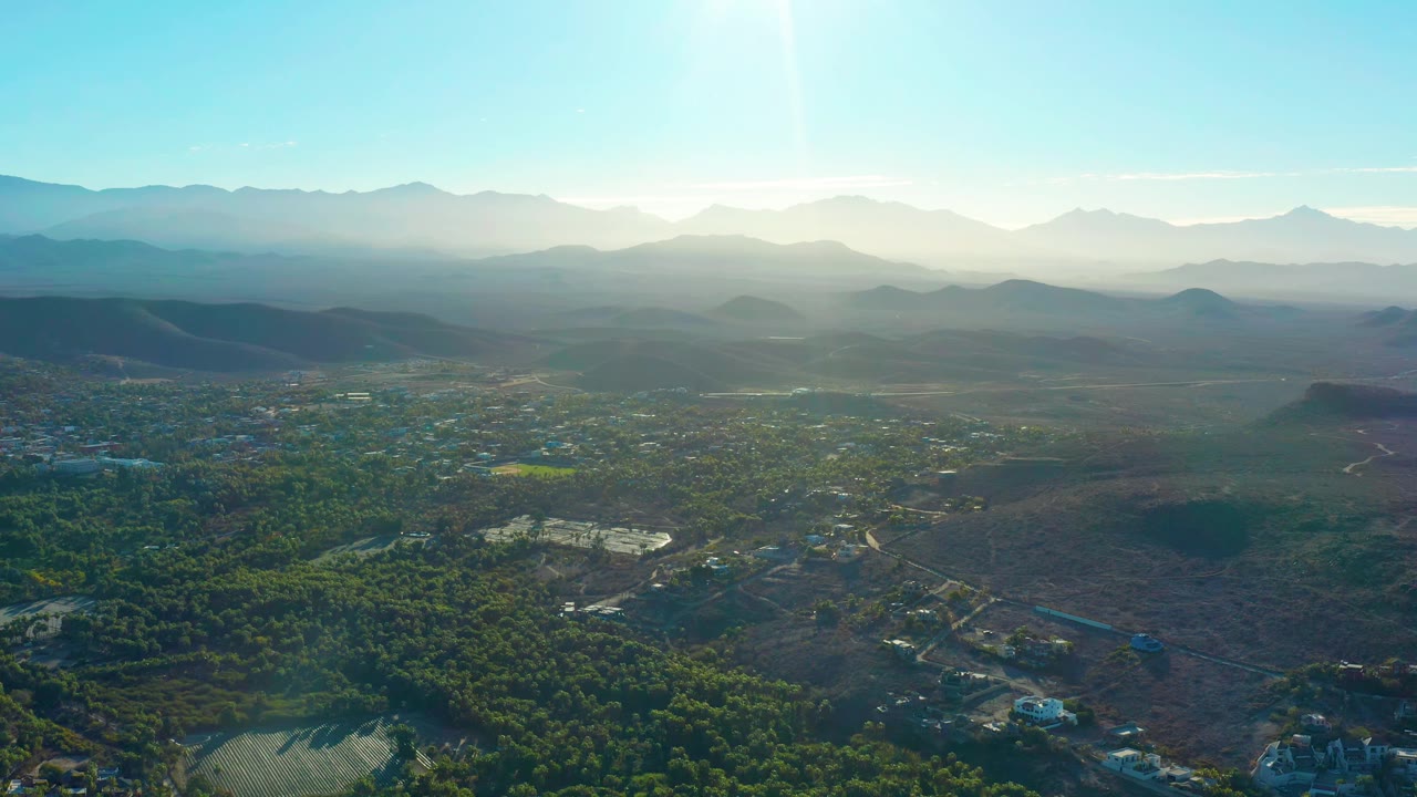 Wide drone view of valley settlement under bright sun
