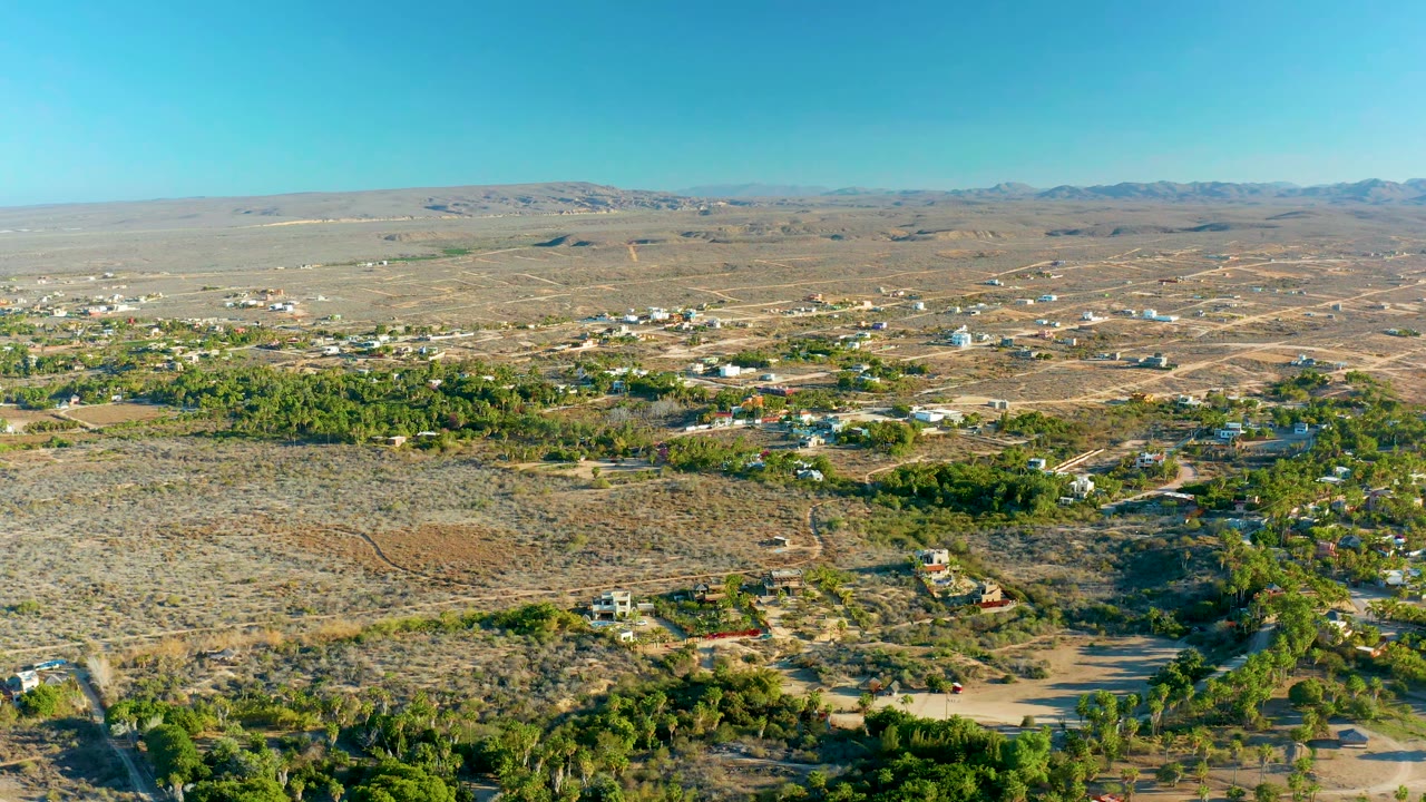 Desert lots and green patches spread across a small settlement under clear sky.