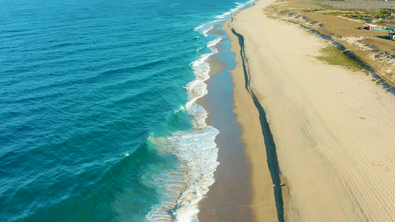 Aerial view of blue ocean waves reaching a sandy beach
