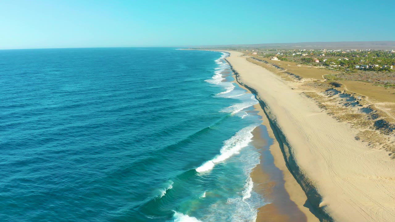 Long aerial coastline with surf and open sand