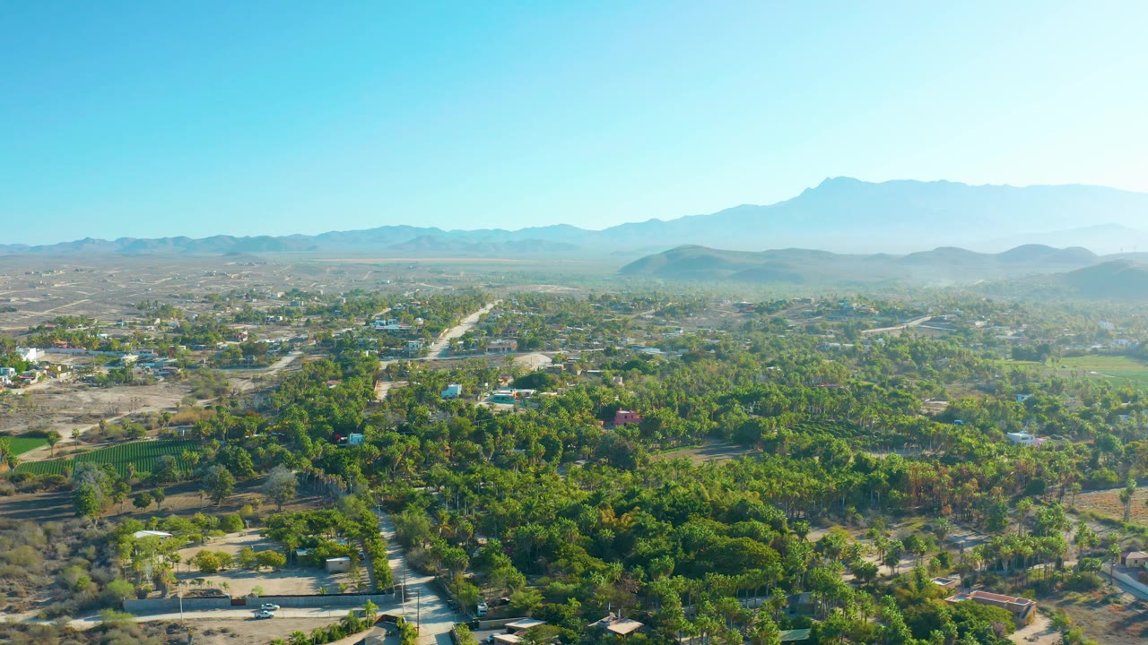 Wide aerial landscape with tree-lined roads and mountains in haze