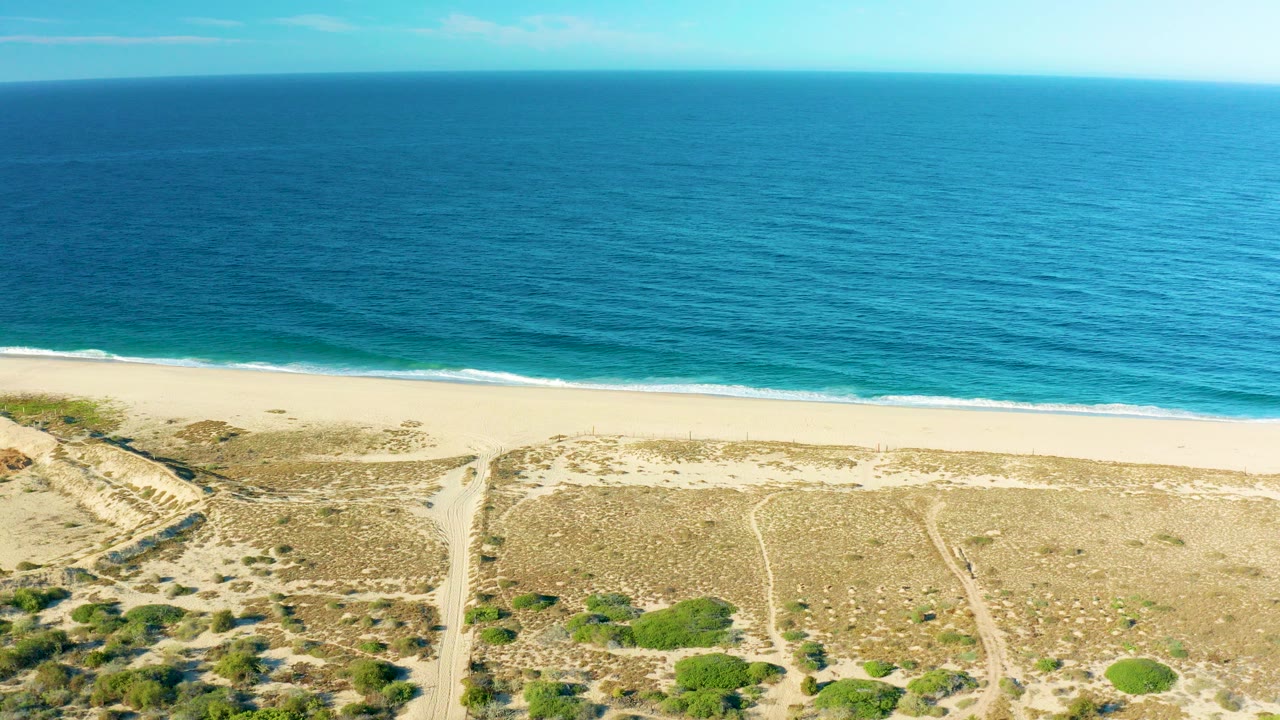 Aerial view of blue ocean, sandy beach, and coastal dunes.