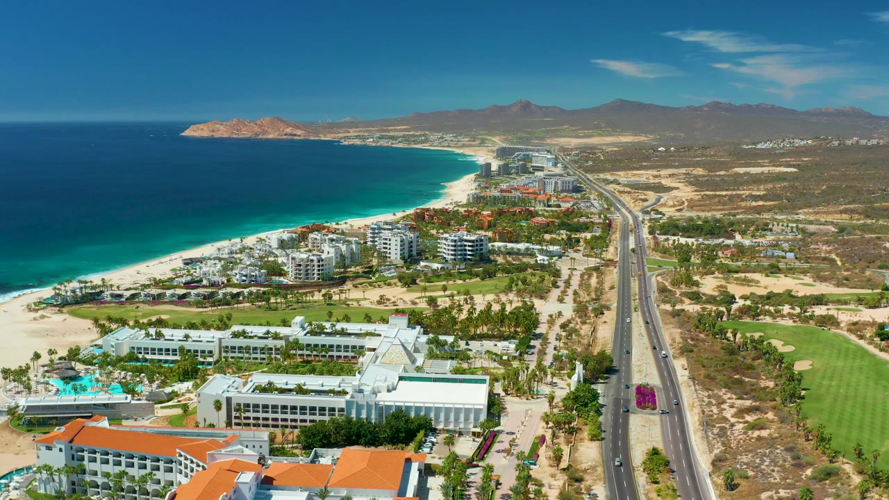 Wide drone view of beach resorts and highway along the coastline.