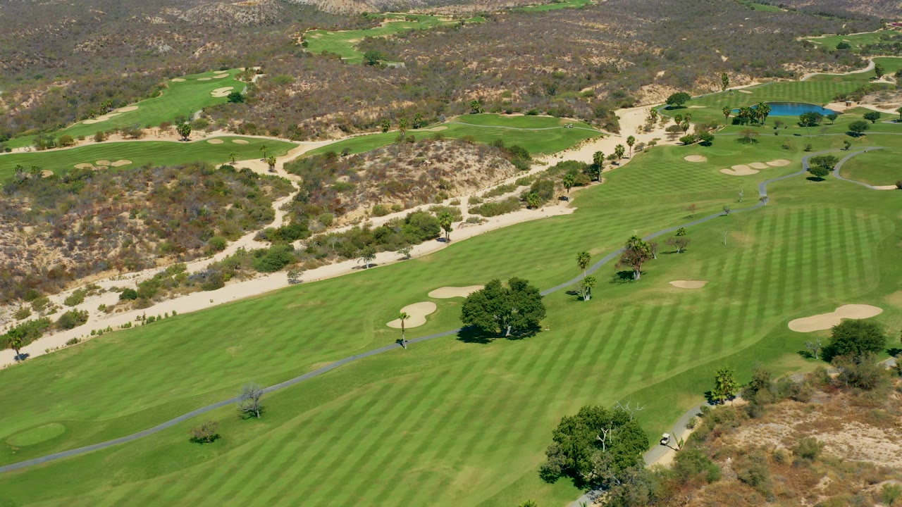 Mid-clip aerial frame of the Marquis Los Cabos golf course, with the fairway running through the center, sand bunkers on both sides, and no visible people.