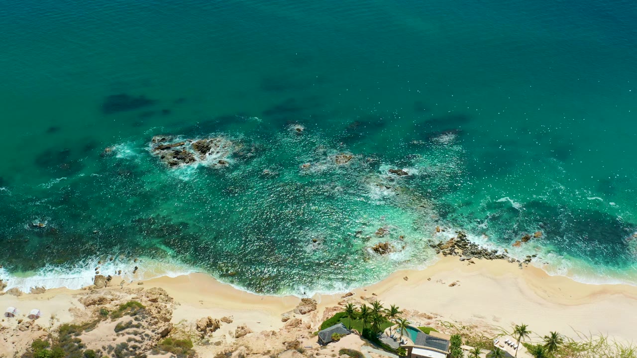 Rocky surf zone with turquoise water and sandy beach below