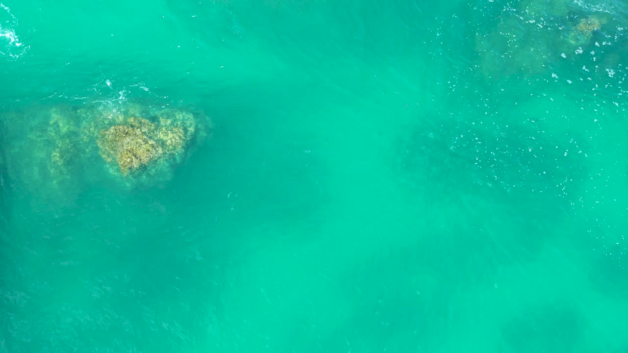 Turquoise water with a submerged rock near the upper left.