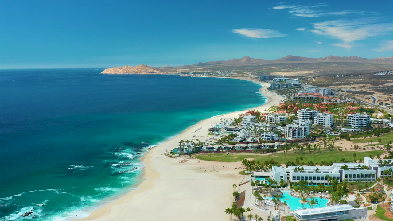 Fourth frame shows a slightly lower portion of the Marquis Los Cabos beachfront, with white surf breaking near rocks, green resort landscaping, pool water, sand, and no visible people.
