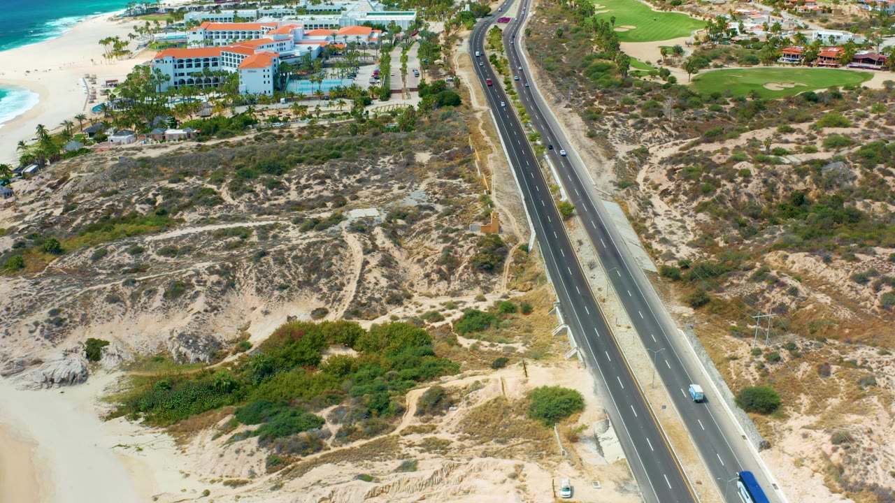 A blue bus and cars move along the coastal highway.