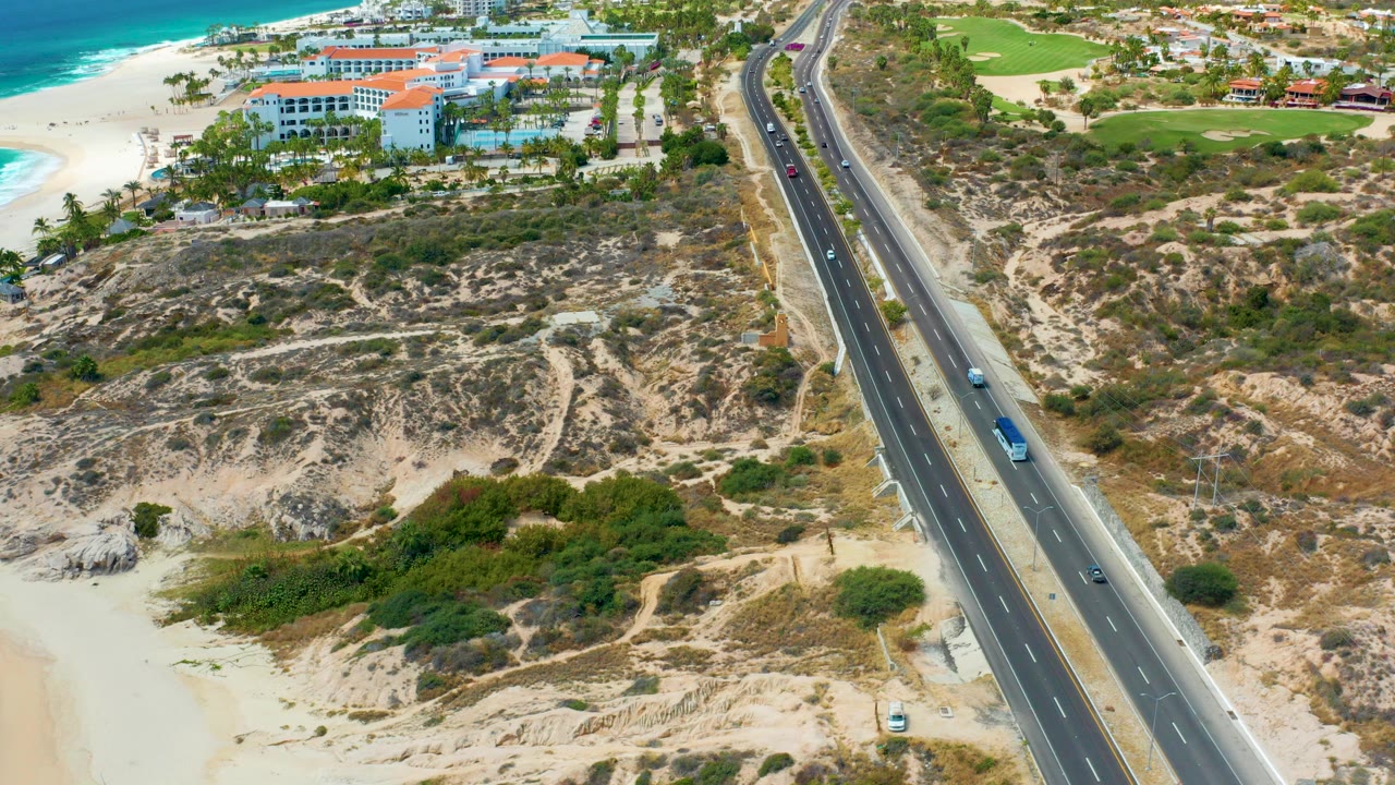 Aerial view of coastal highway beside beach and resort buildings.