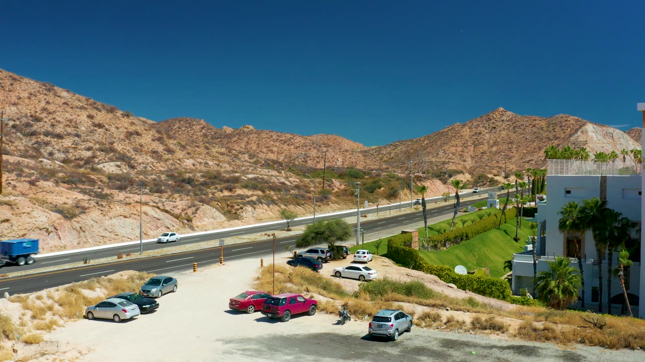 Truck exiting highway frame with parking lot and mountains behind.