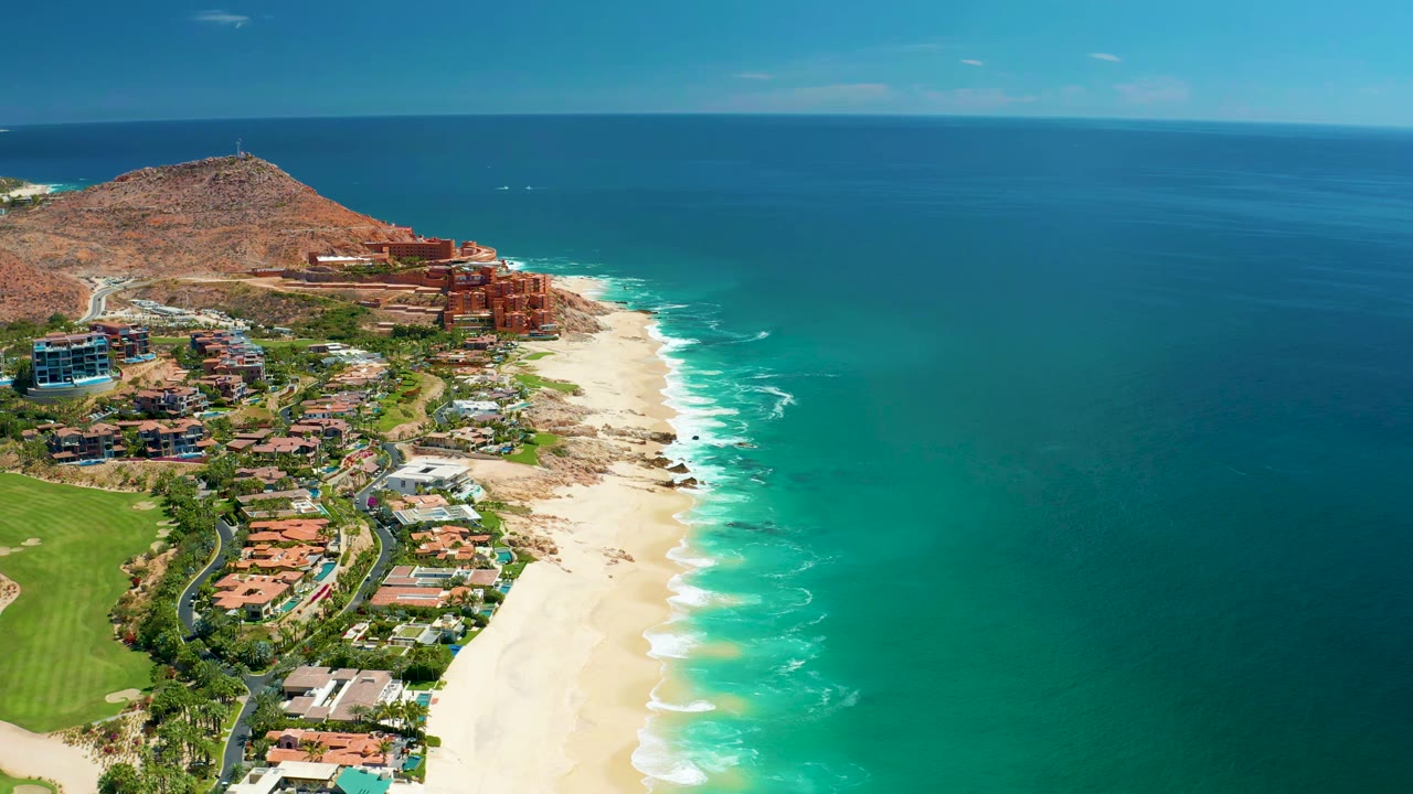 Aerial coastline view with resort buildings beside a bright sandy beach