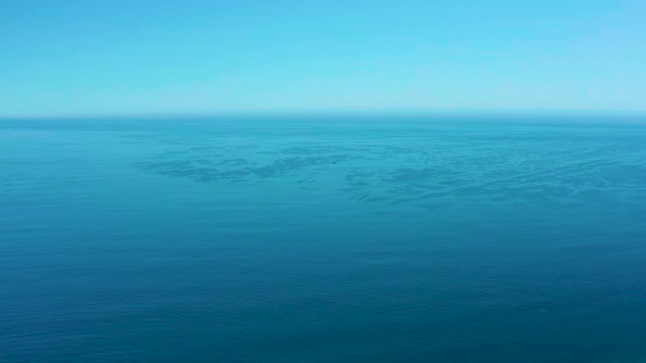 Opening frame of the Marquis Los Cabos clip showing a wide blue ocean surface beneath a clear sky, with faint darker water patches and no visible people.