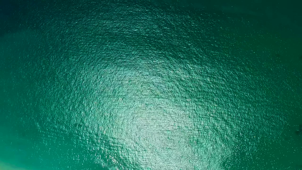 Ocean ripples with darker water along the upper left.