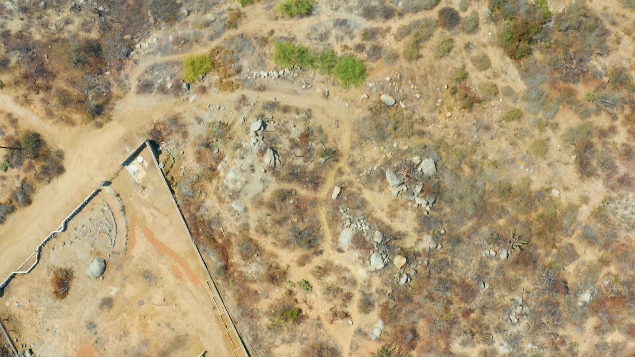 Aerial view of rocky desert terrain and corner of a walled lot.
