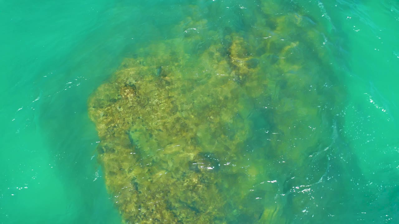 Large underwater rock in turquoise water