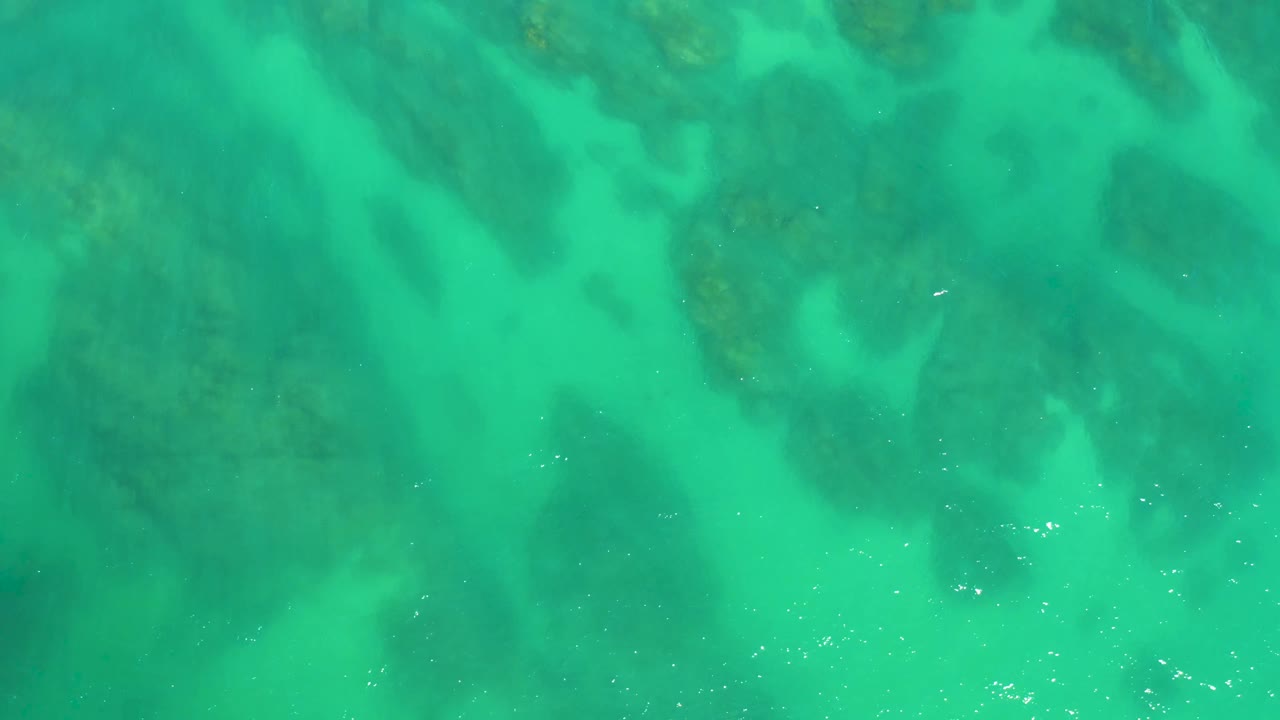 Clear green-blue water with submerged rock patches.