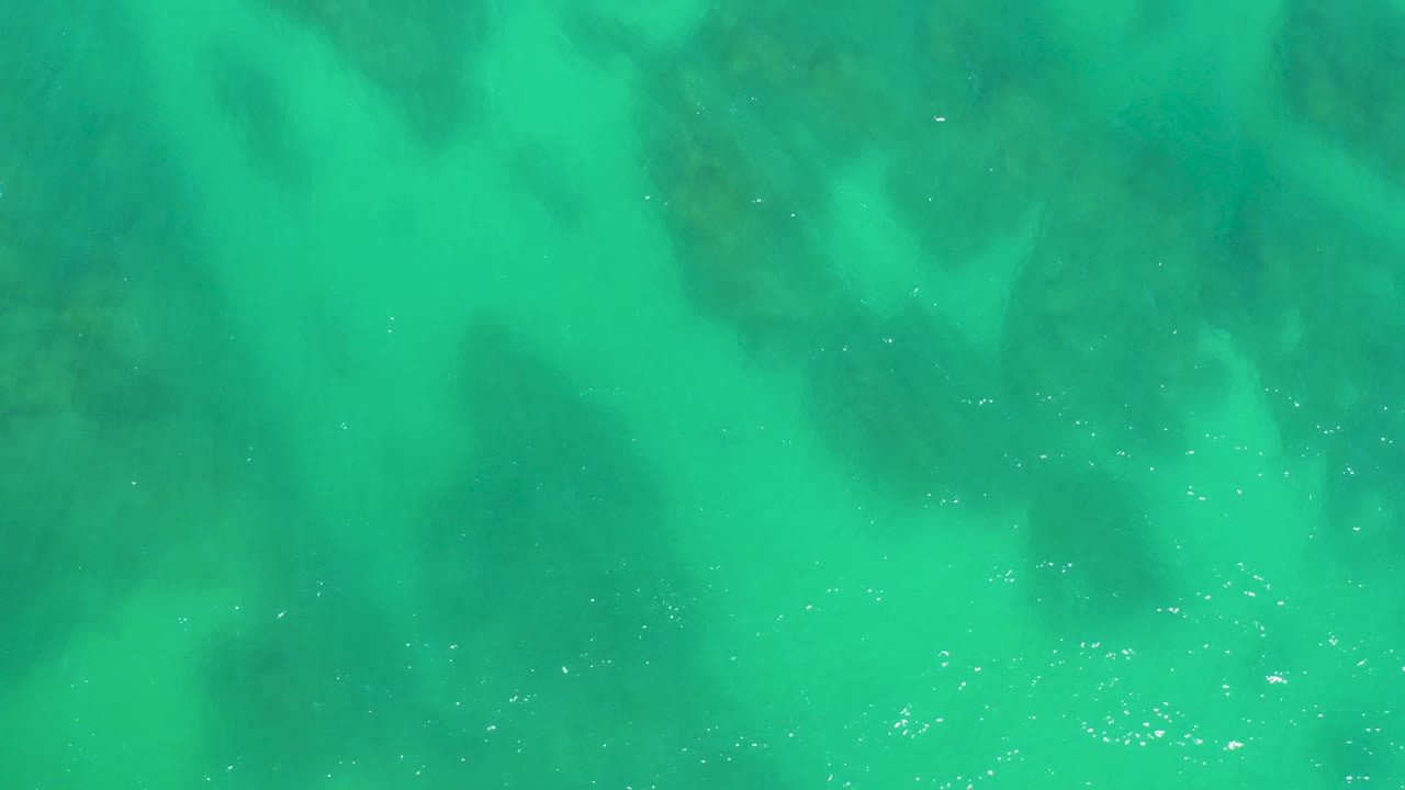 Turbulent turquoise water partly obscuring underwater rocks