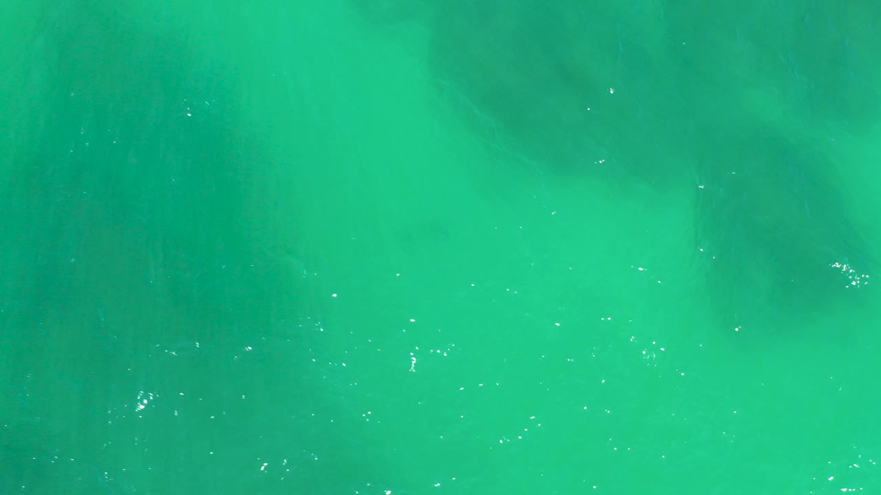 Turquoise ocean water with darker underwater rock patches.