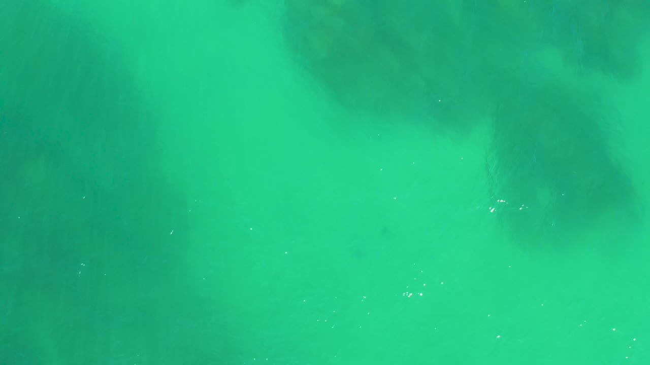 Green-blue water at Dreams Los Cabos shows soft shadowed rock or coral forms under the surface, with no visible people.