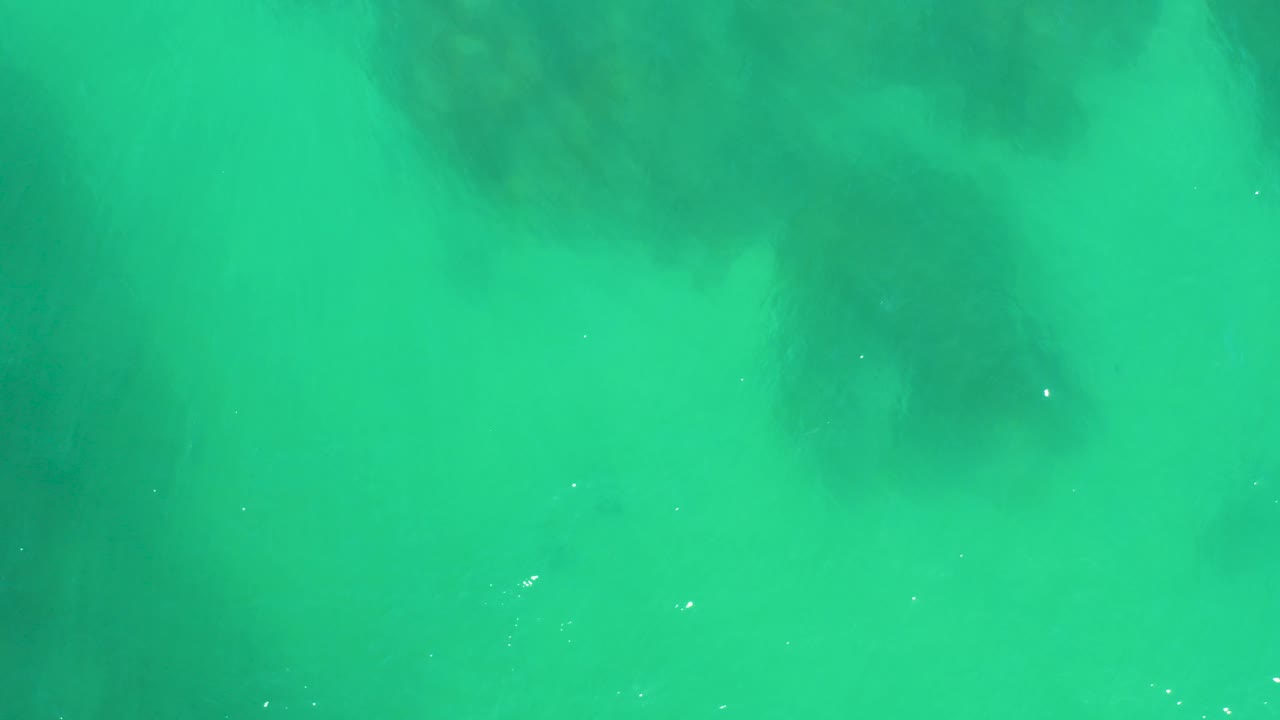 Bright turquoise water over blurred underwater rocks