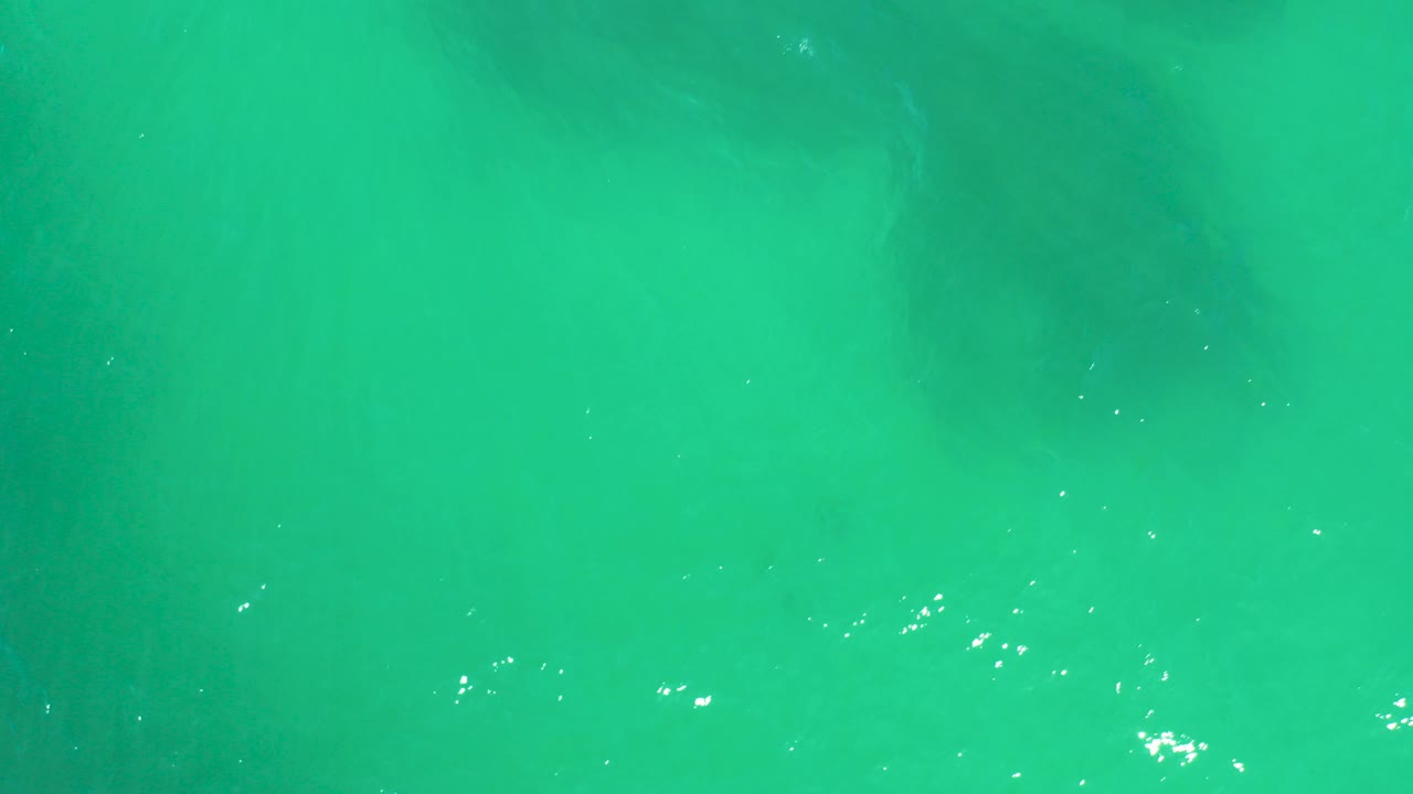 Clear turquoise ocean water with faint underwater shadows and small light reflections.