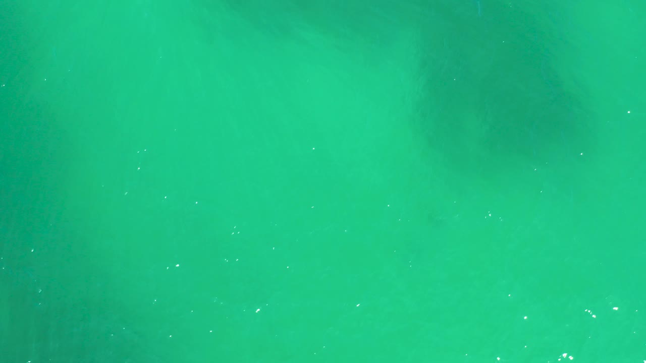 Midway through the clip, transparent green-blue water at Dreams Los Cabos fills the frame, with muted darker shapes below the surface and no visible people.