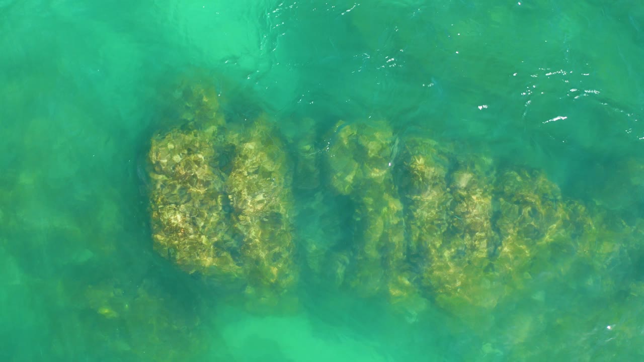 A shallow turquoise section at Dreams Los Cabos shows submerged rock shapes under a slightly hazier layer of ripples, with no visible people.