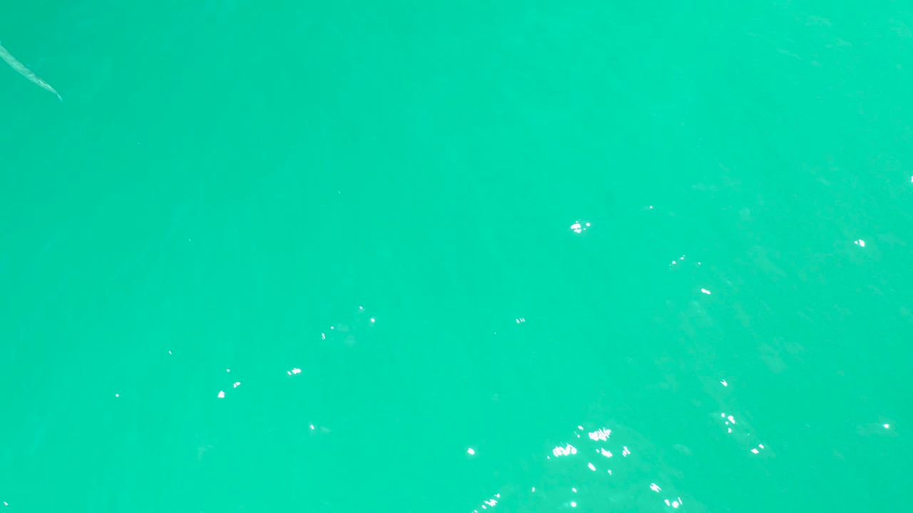 Clear turquoise water fills the frame at Dreams Los Cabos, with bright white reflections and the fish faintly visible near the upper area, no visible people.