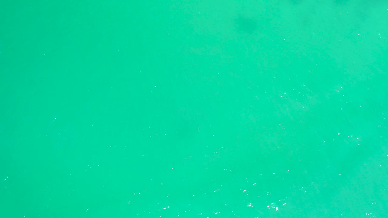 Green-blue ocean surface at Dreams Los Cabos with faint pale underwater clouding and no visible people.