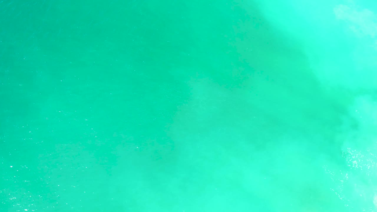 The second frame shows bright surface wash over clear turquoise water at Dreams Los Cabos, with the dark marine animal shadow slightly more defined and no visible people.