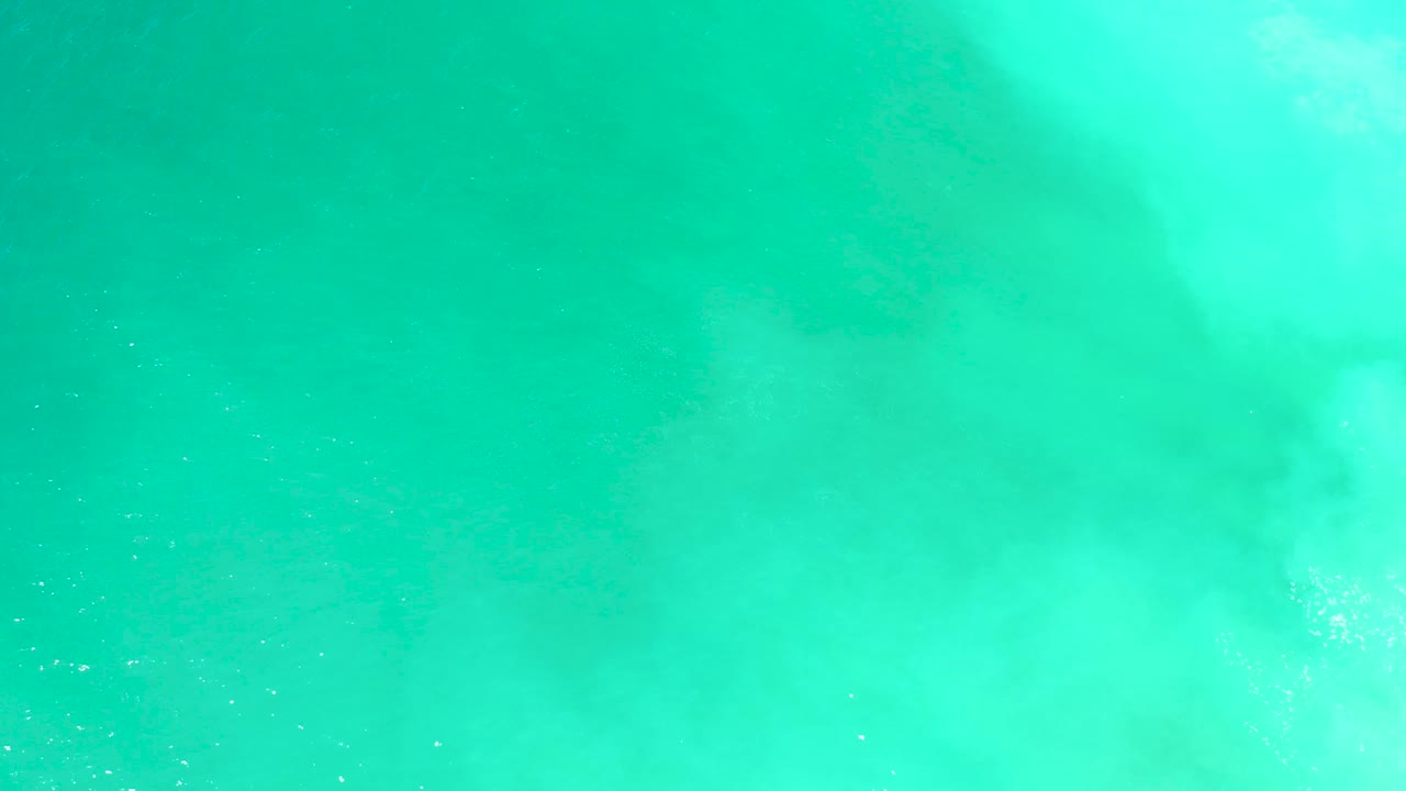 Turquoise water at Dreams Los Cabos is crossed by a pale surface pattern while a faint dark shadow remains below the surface, with no visible people.