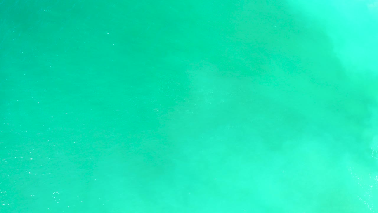 Clear turquoise water at Dreams Los Cabos with soft underwater sand shapes near the upper frame and no visible people.