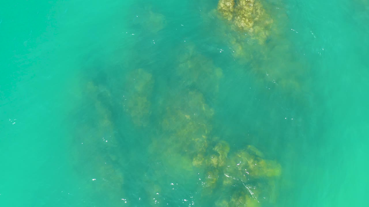 A large submerged rock formation fills the center of the frame beneath shallow turquoise water at Dreams Los Cabos, with no visible people.