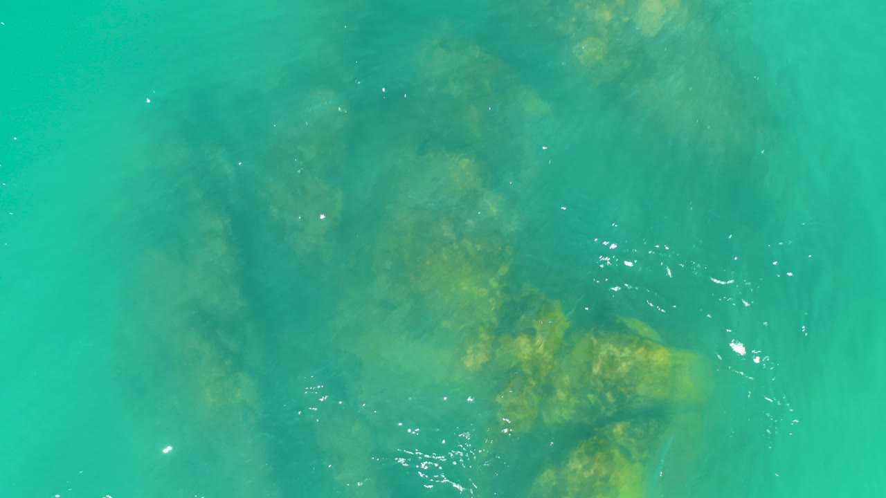 Turquoise water over submerged rocks and coral