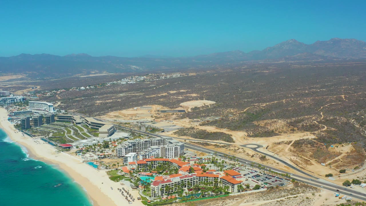 Aerial view of Los Cabos beach resort area beside a coastal road.