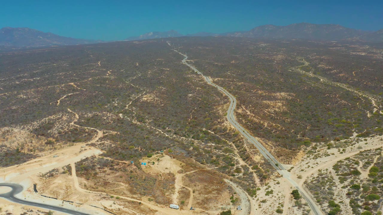 High aerial view of road curves across dry desert terrain