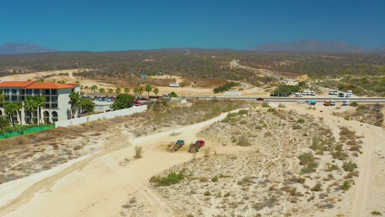 Aerial view of sandy desert road, traffic, and red-roofed building