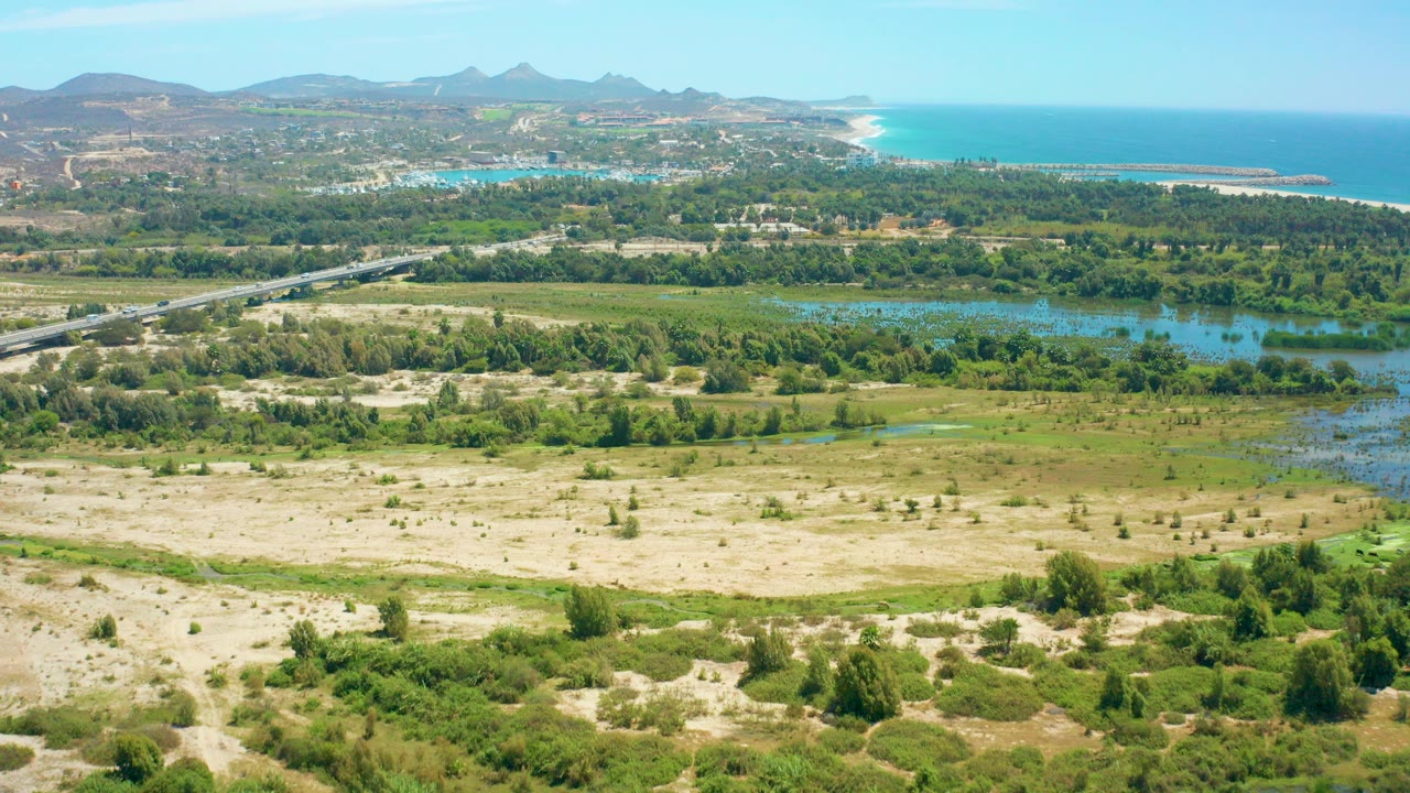 Aerial view of dunes, wetlands, road, coastline, and mountains.