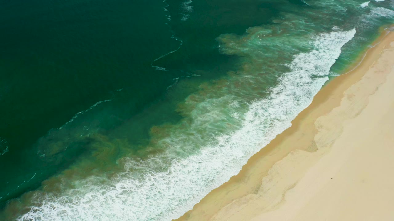 Overhead view of surf meeting a sandy beach